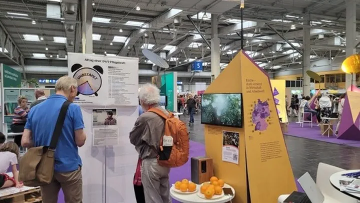 Besucher auf dem Kirchentag informieren sich zu Arbeitsausbeutung in der häuslichen Pflege.